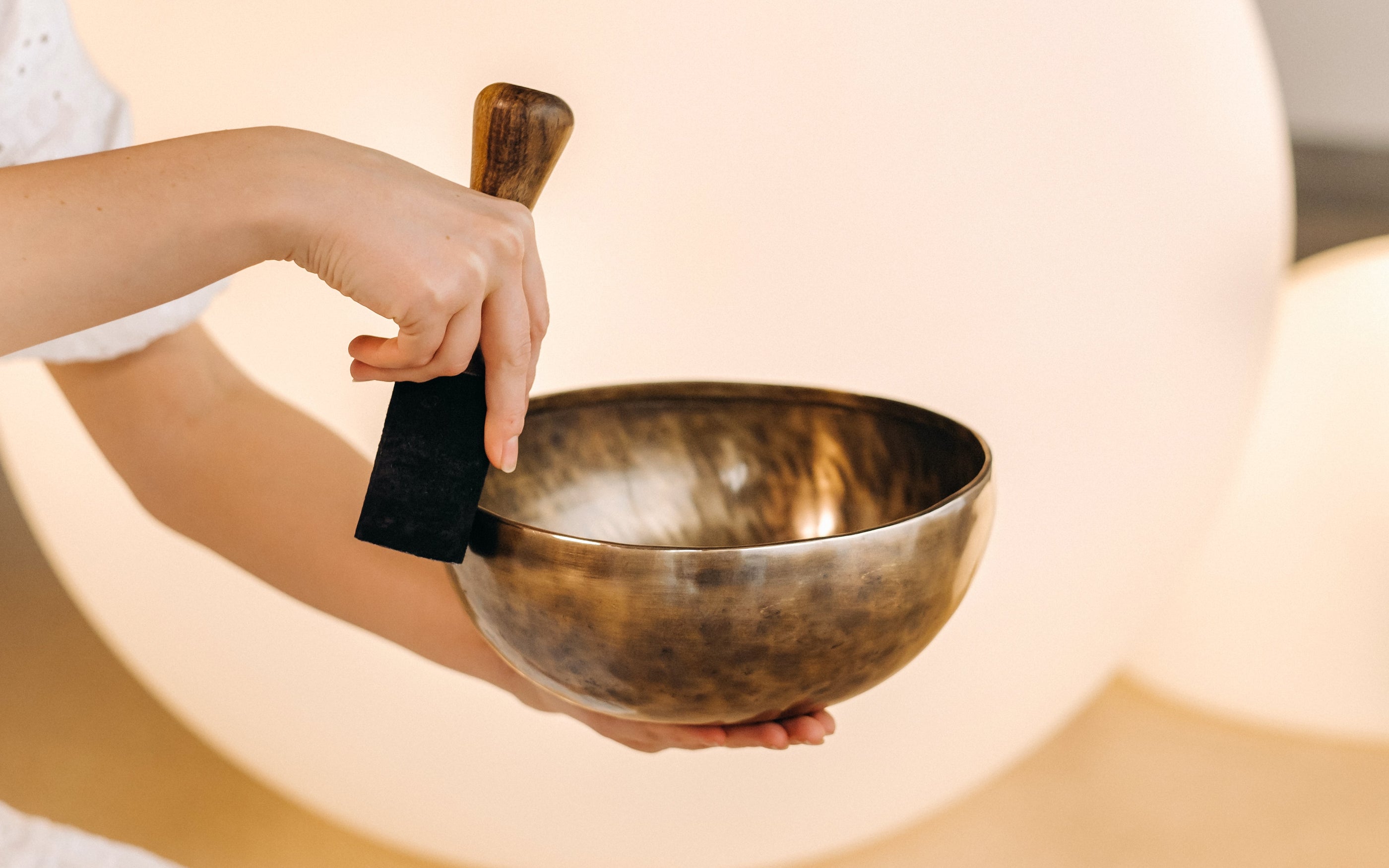 Person playing a handcrafted Tibetan singing bowl, demonstrating the resonance and quality of devoted artisan craft