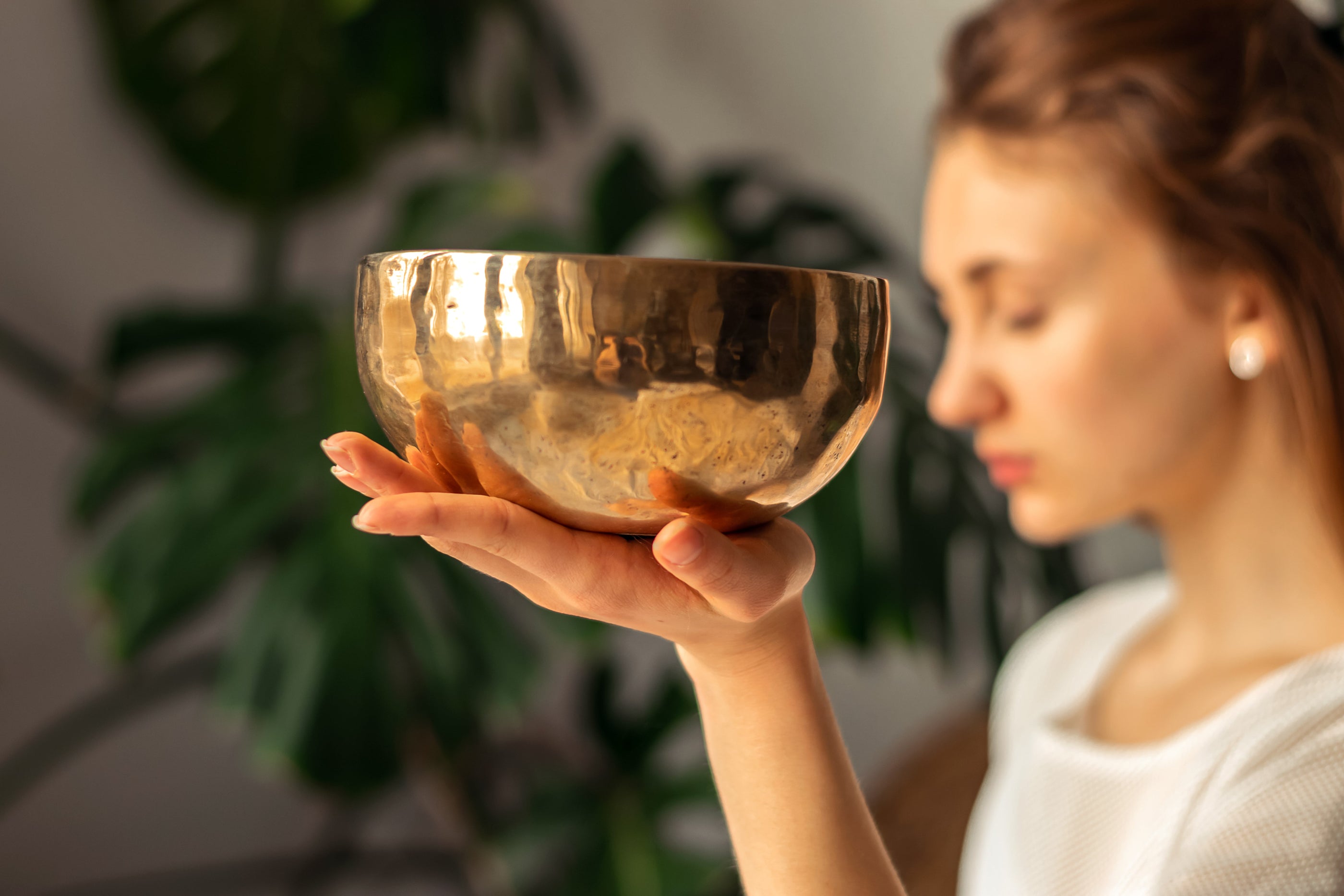 Woman holding a Serene Streams Tibetan singing bowl indoors, caring for her handcrafted bowl from Kathmandu Nepal