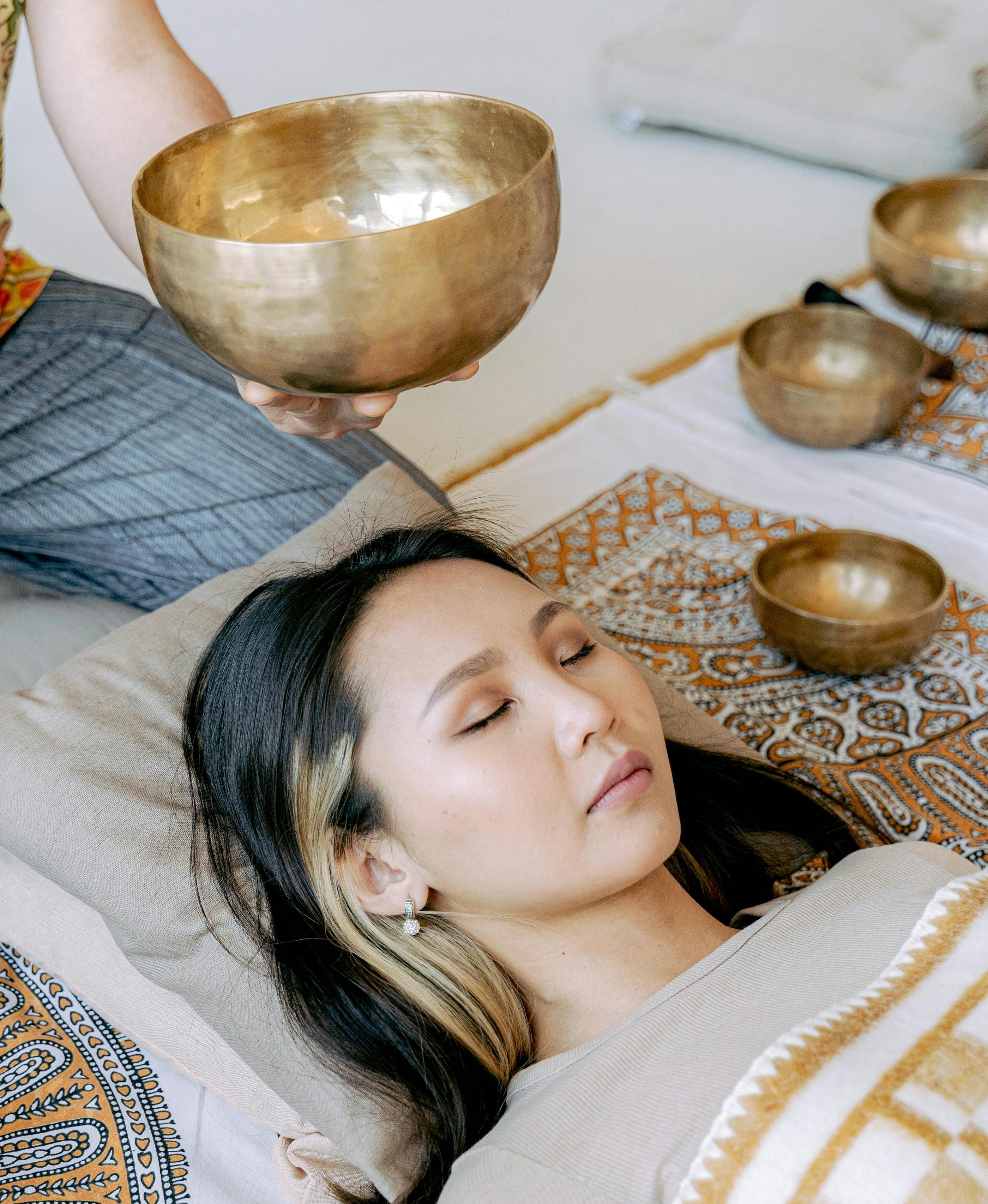 Woman in a sound bath with a Tibetan singing bowl experiencing the scientifically proven benefits of healing frequencies