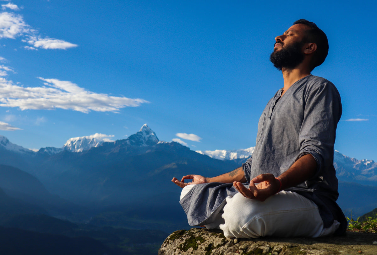 Man meditating in a serene mountain landscape, drawing forward the peace within through Serene Streams Tibetan singing bowl philosophy